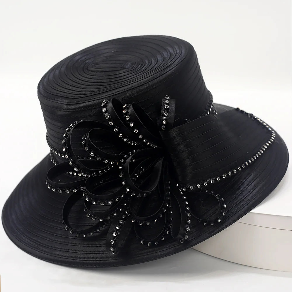 Close-up view of a luxurious black satin church hat adorned with crystals and a large ribbon accent, perfect for formal church events.