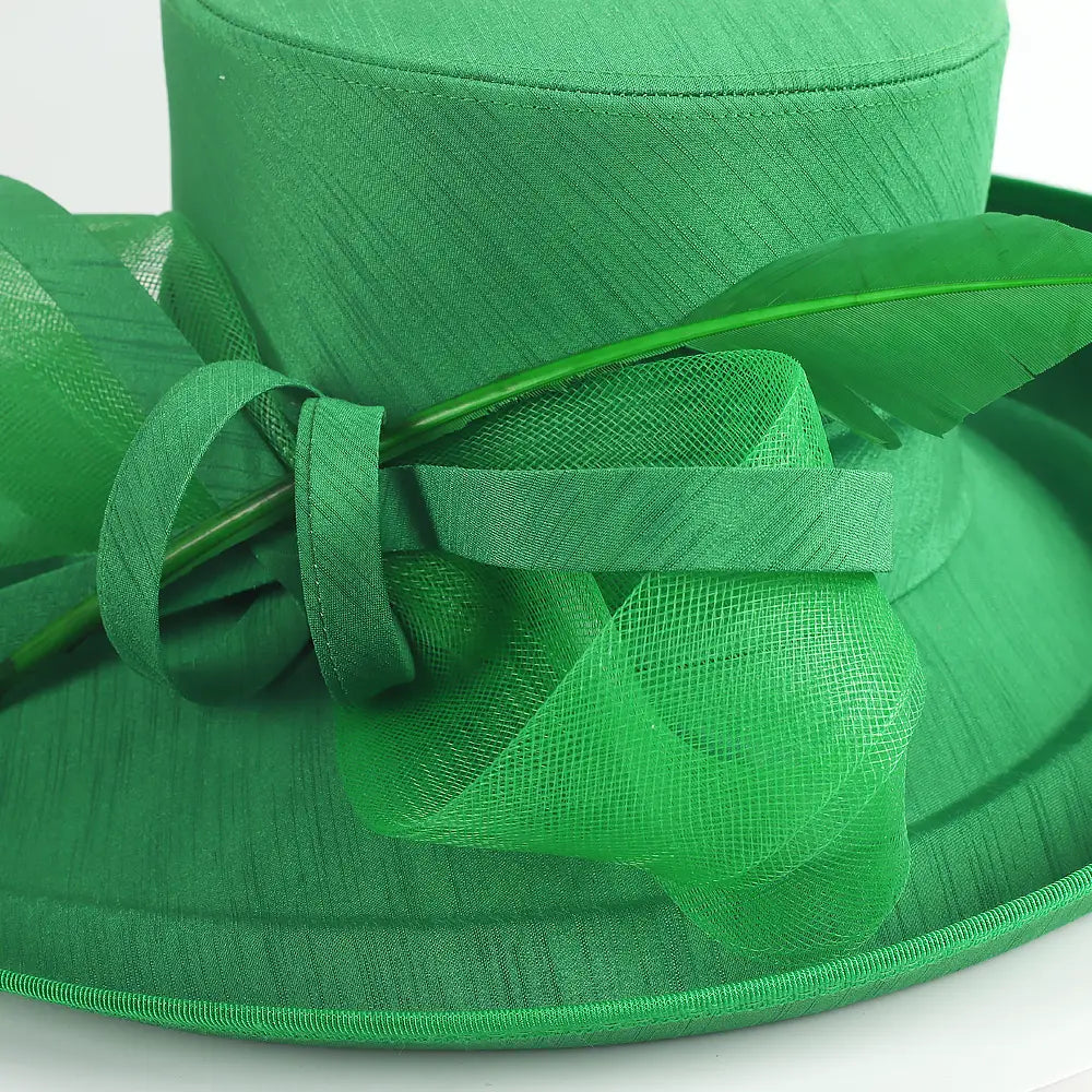 Close-up of green church hat with feather and mesh bow embellishment – FORBUSITE