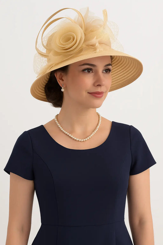 Champagne beige church hat with floral details for tea party or derby events – model wearing navy dress with pearl necklace