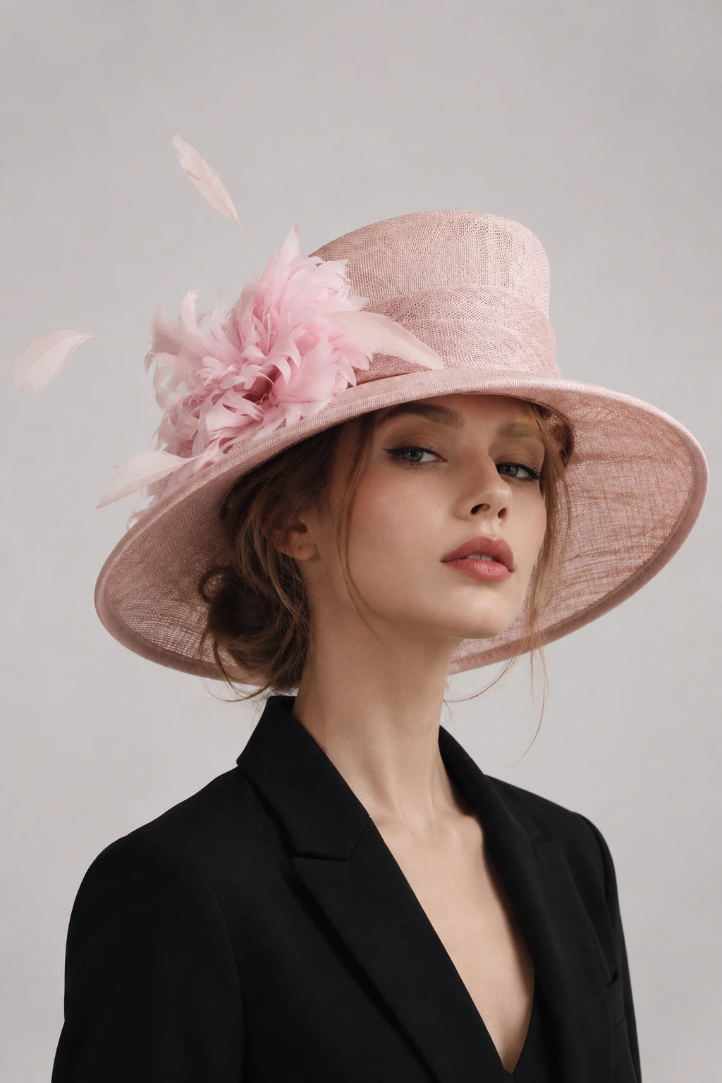 Elegant blush pink wide brim sinamay church hat for women with floral and feather decorations.