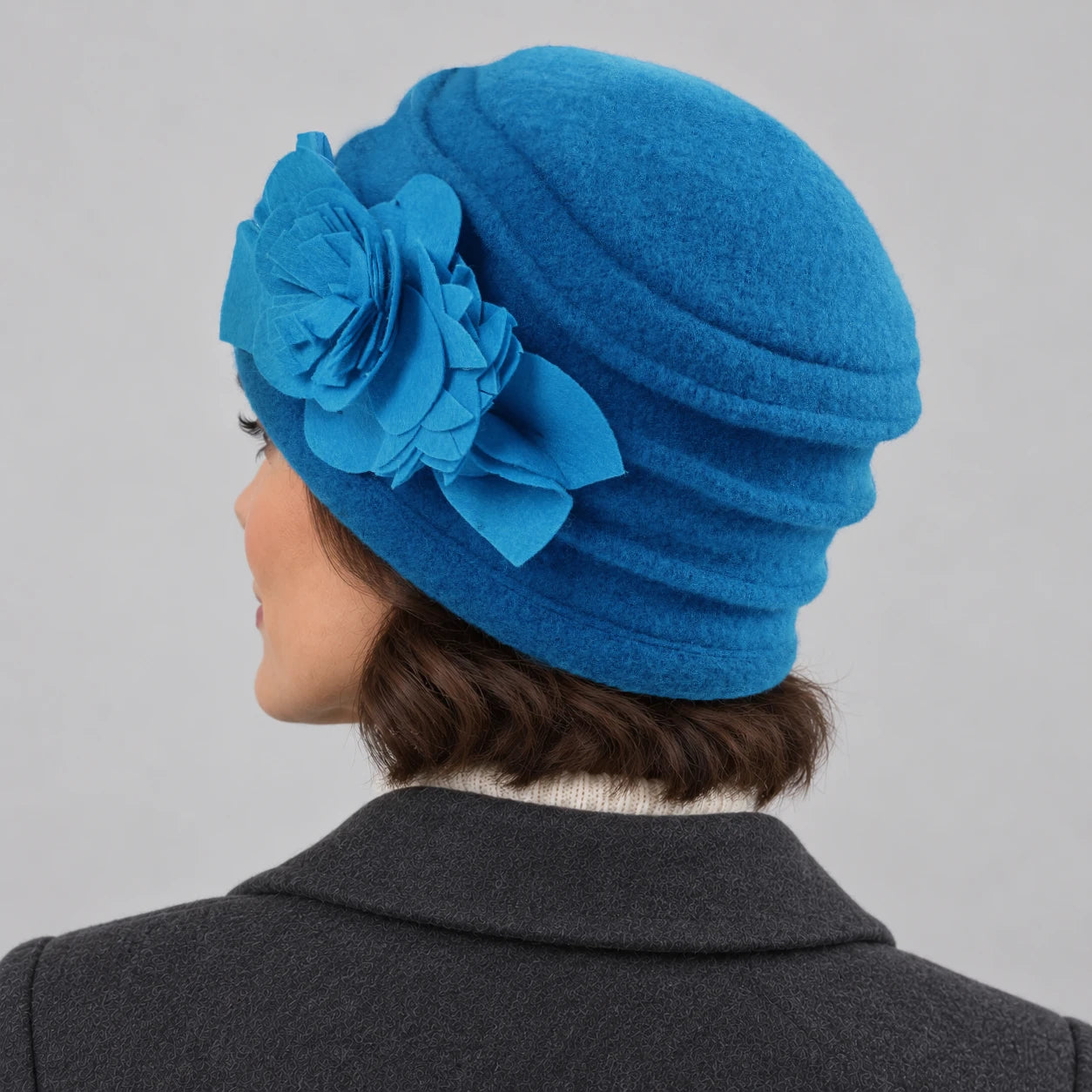 Rear side view of a bright blue brimless wool cloche hat showing layered crown ruching
