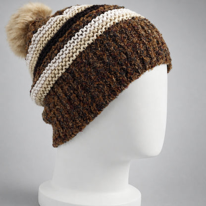 Side back view of a brown striped knit beanie with a fixed faux fur pom pom