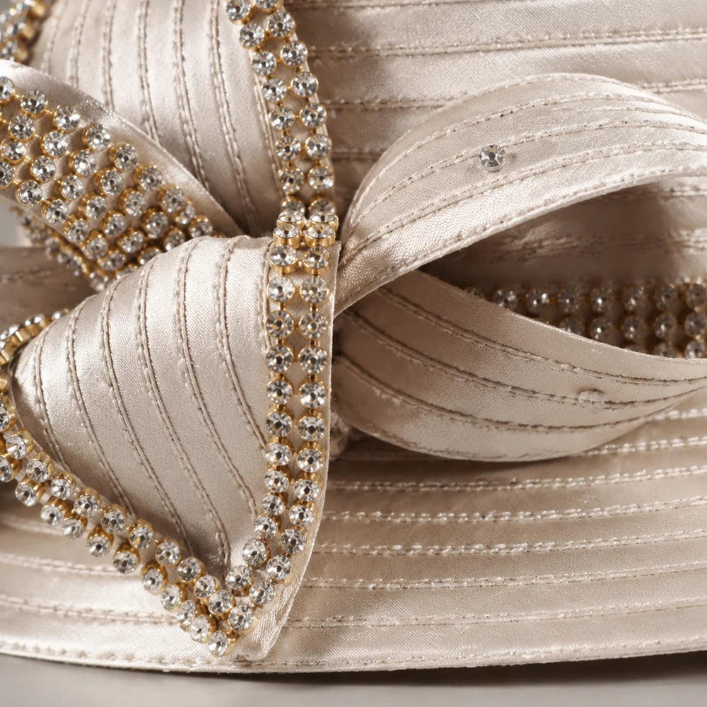 Close-up of champagne church hat with satin fabric and sparkling rhinestone bow, elegant formal hat for women’s church events, weddings, and special occasions