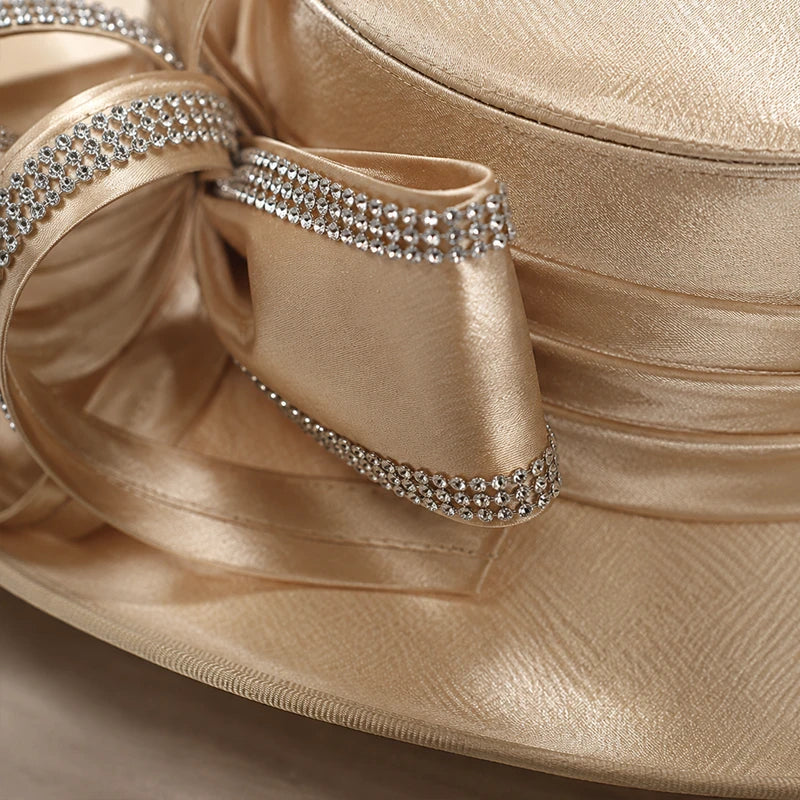 Close-up of champagne church hat featuring sparkling rhinestone ribbon trim and luxurious satin texture, premium women’s dress hat