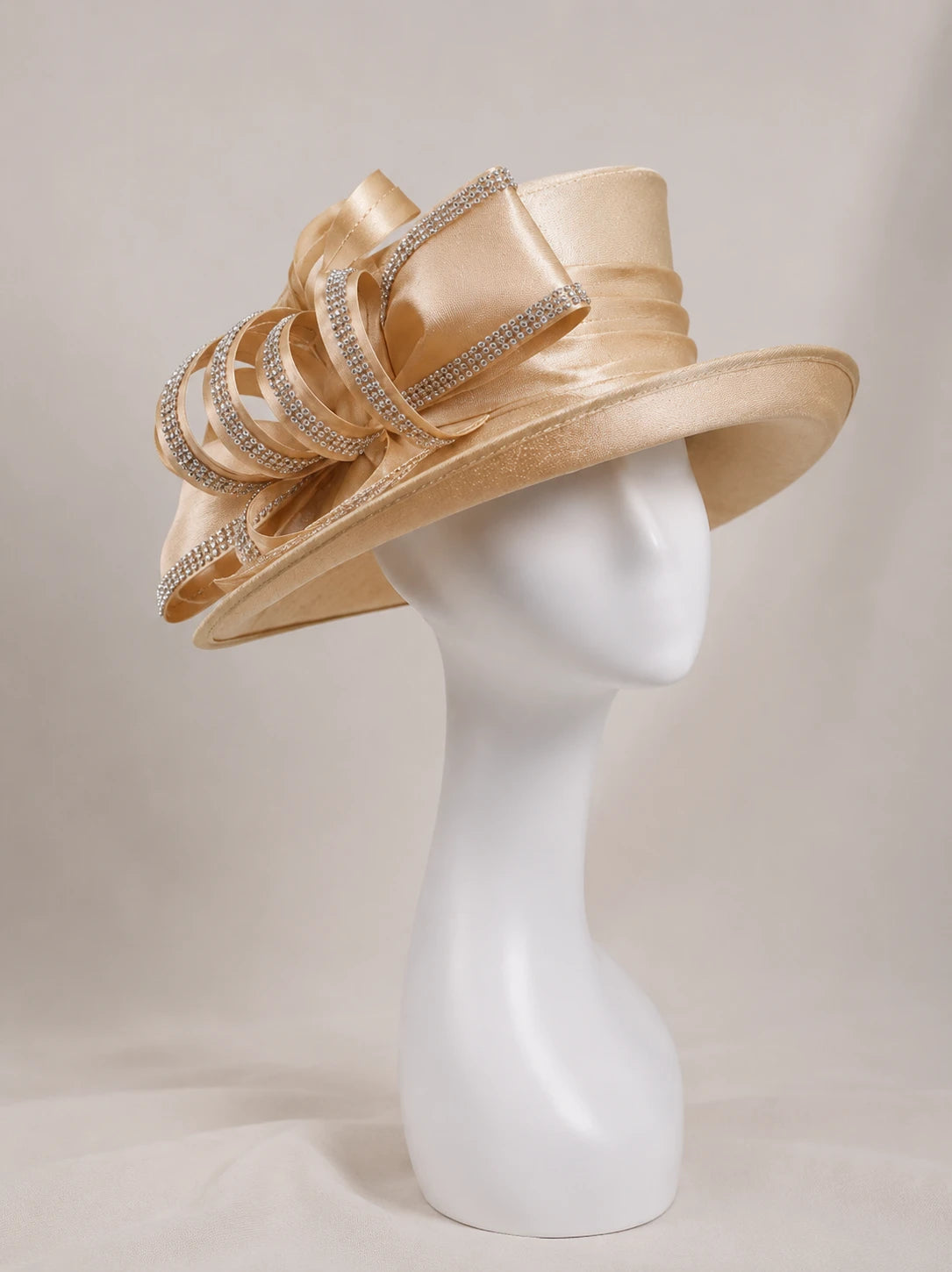 Side view of champagne wide brim church hat on mannequin with rhinestone ribbon bow, elegant women’s formal occasion hat