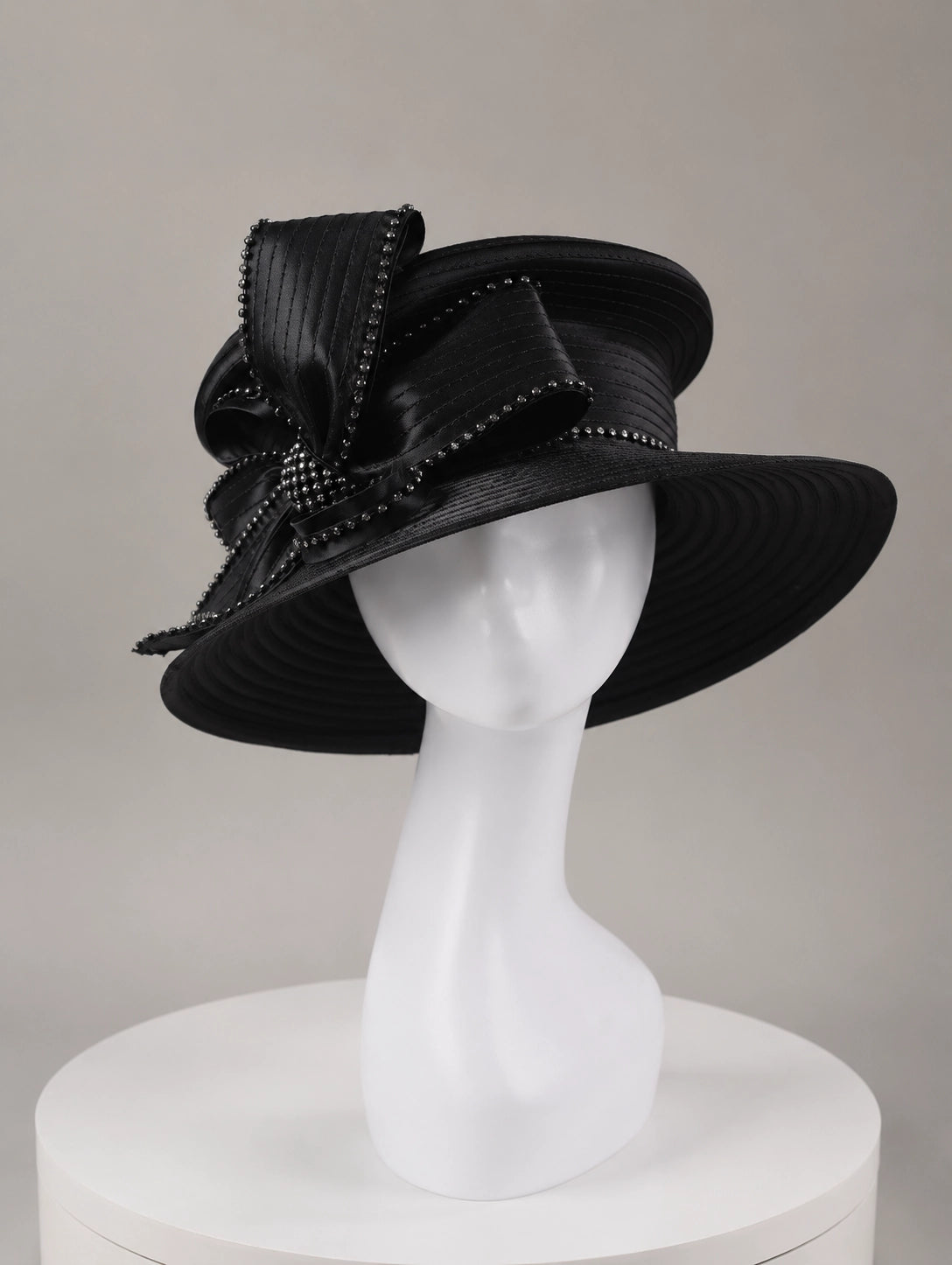 Front view of stylish black church hat worn by model, featuring rhinestone decorations and high-end formal style