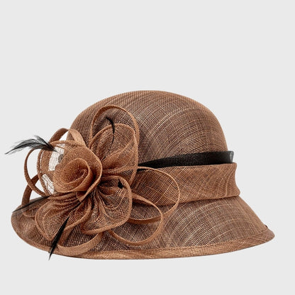 Elegant brown cloche sinamay hat with a large flower and feather detailing, perfect for formal events like weddings and church services.