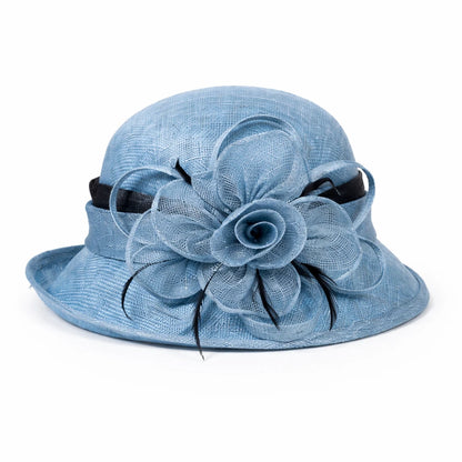 Light beige cloche sinamay hat with a black flower and feather detail, an elegant choice for upscale gatherings and formal celebrations.