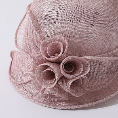 Close-up of a pink cloche sinamay hat with intricate flower detailing, ideal for formal events and weddings.