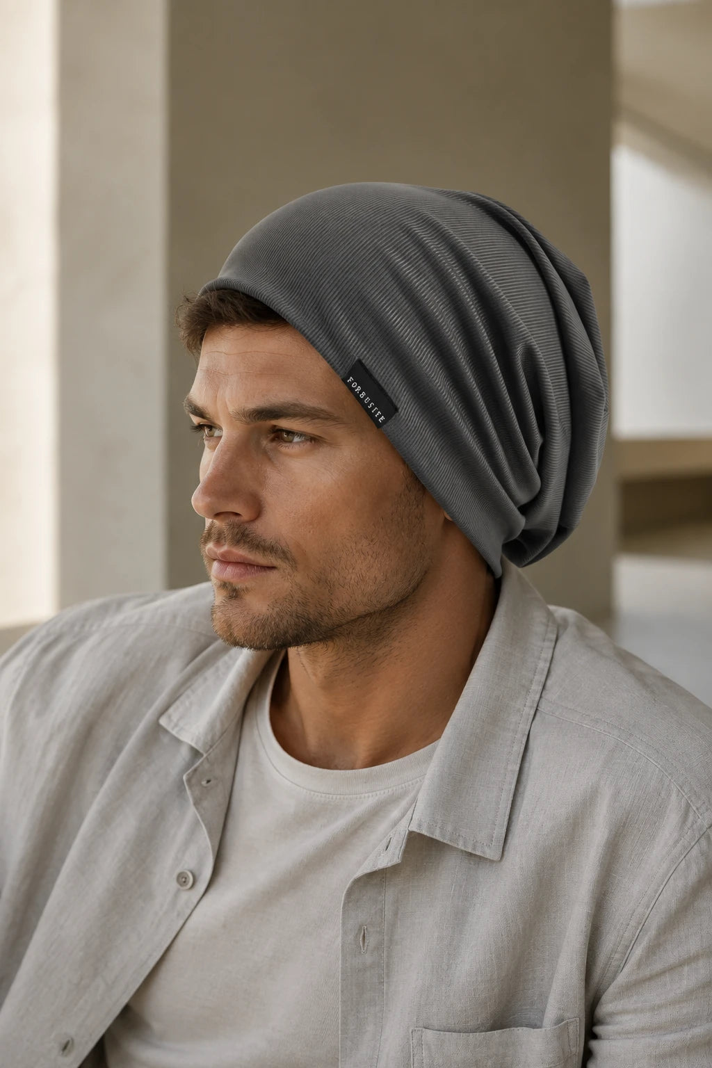 Man styling a dark gray lightweight slouchy beanie with a light casual outfit in mild weather