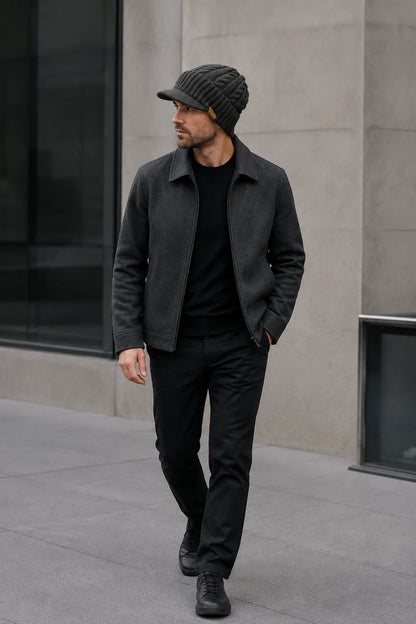 Man wearing a dark gray cable knit visor beanie with a black winter outfit in the city.