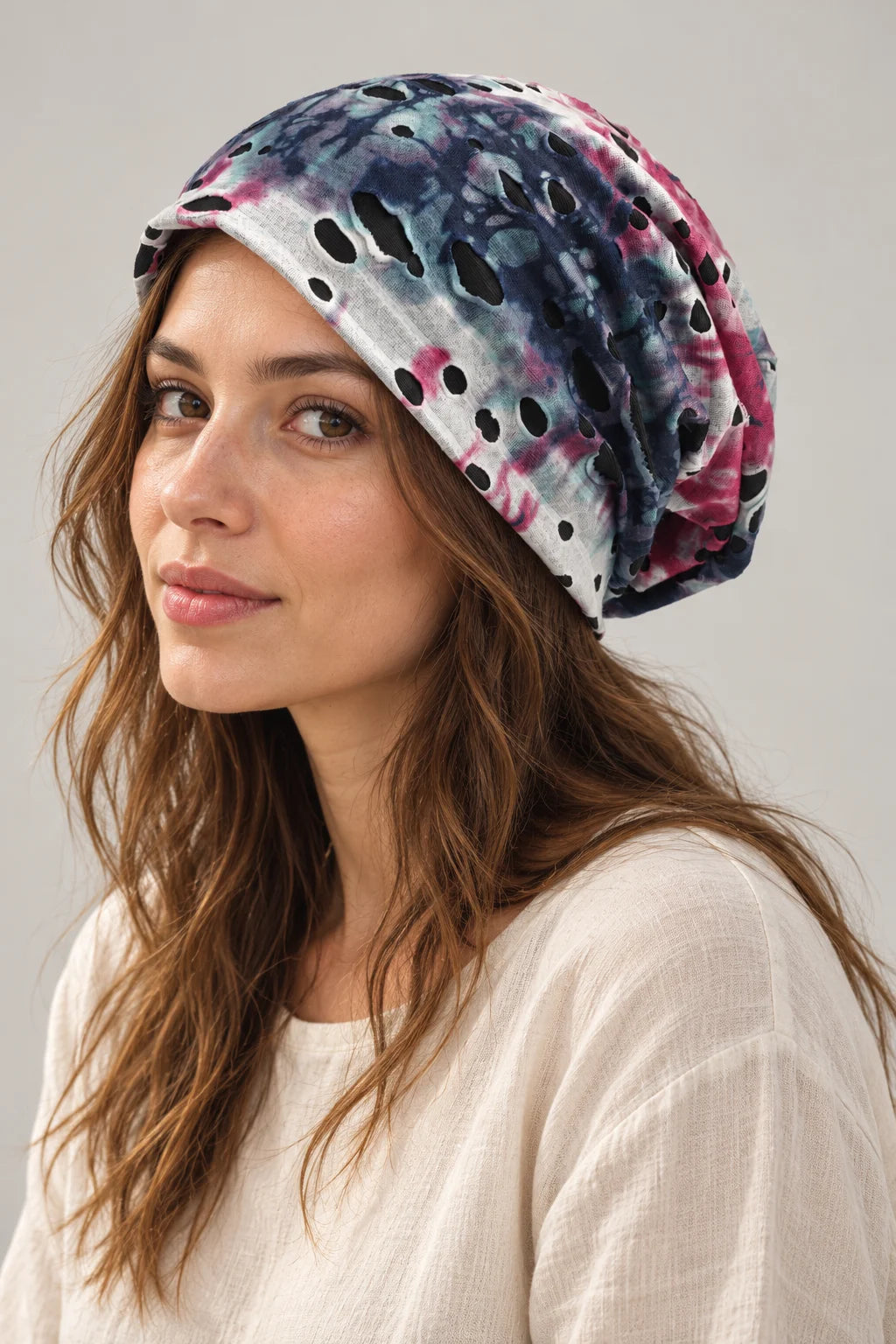 Woman wearing the blue and pink B077 slouchy beanie in a three-quarter view, showing the cutouts and soft drape.