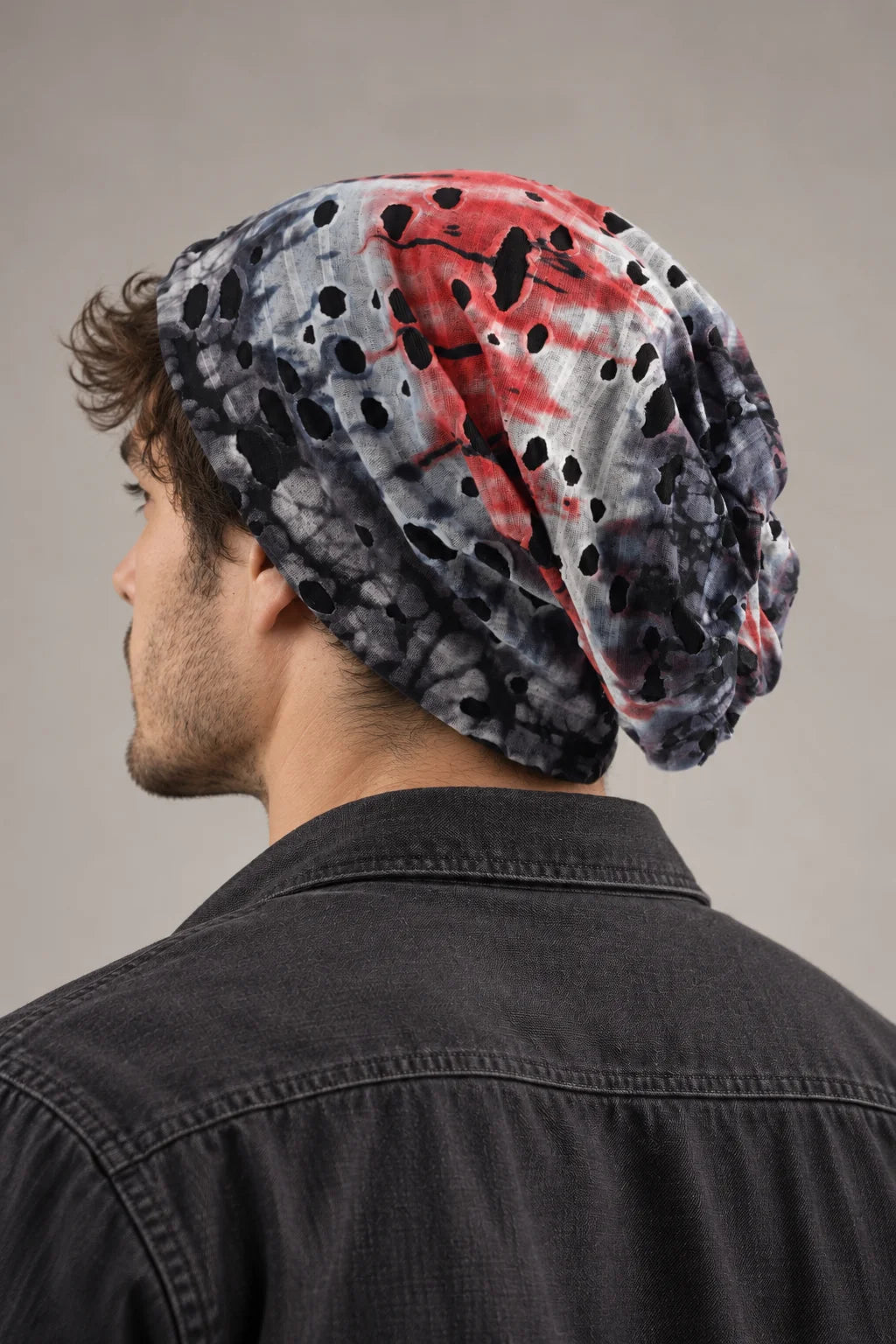 Rear side view of a man wearing the gray and red B077 beanie, showing the loose shape at the back.