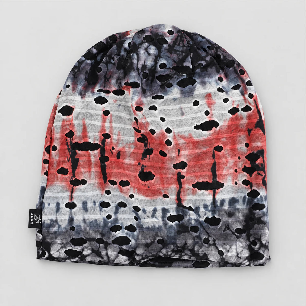 Flat front view of the gray and red B077 tie-dye beanie, showing its irregular cutouts and dark lining beneath.