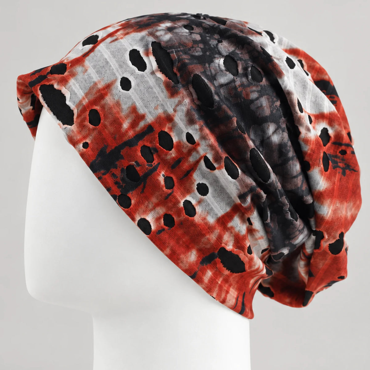 Red, black and white tie-dye B077 slouchy beanie on a white mannequin, showing cutout details and the draped back.