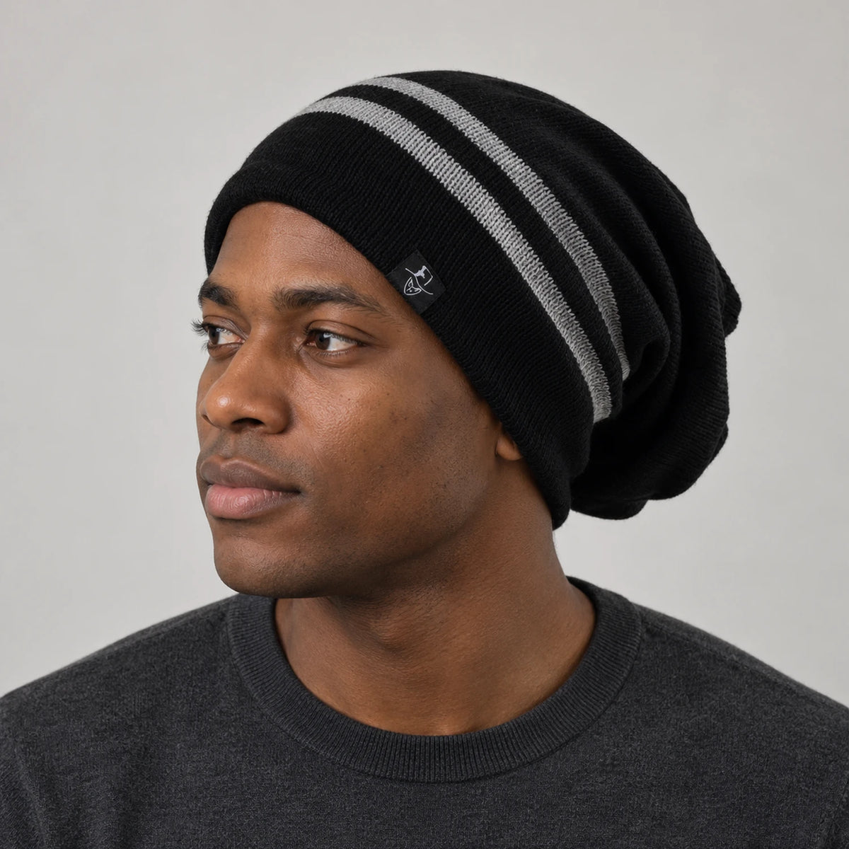 Man wearing a black slouchy beanie with two white stripes in a three-quarter front view.