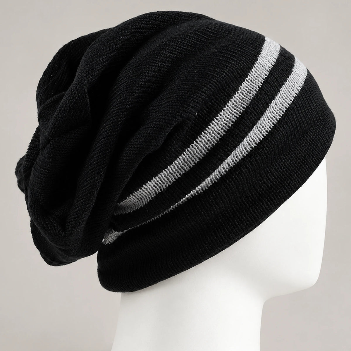 Close side view of the black beanie showing two white stripes, knit texture, and back folds.