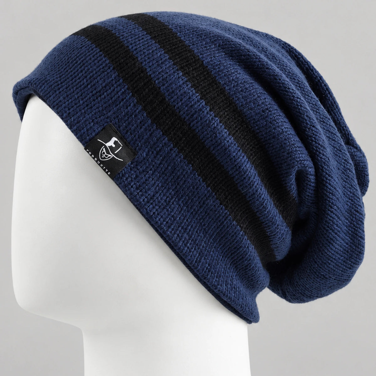 Navy slouchy beanie with two black stripes and a draped back on a white mannequin.