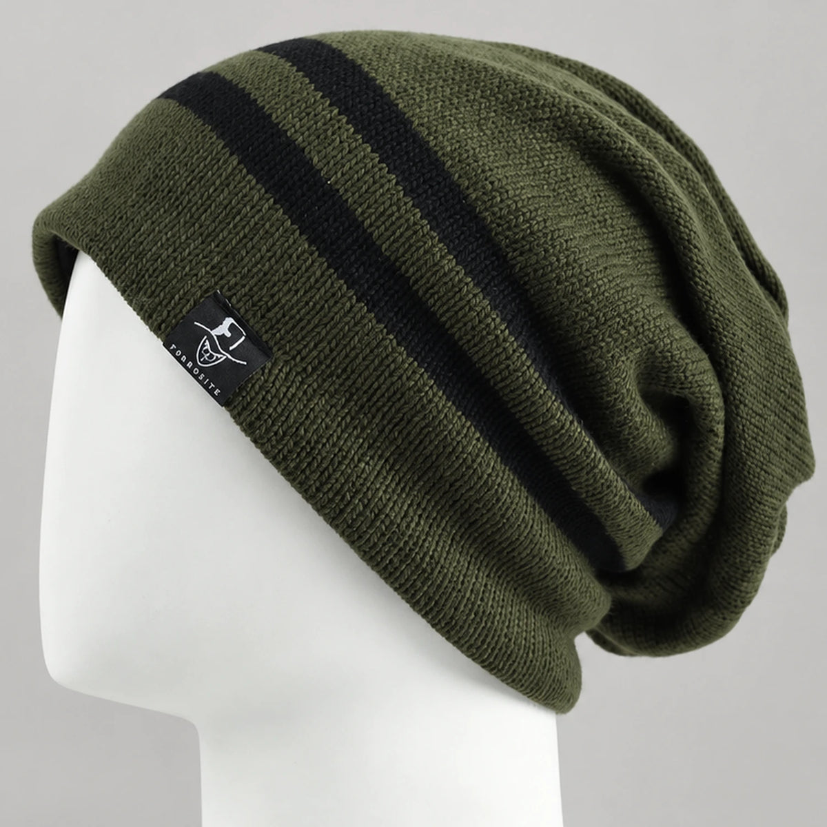 Olive green slouchy beanie with two black stripes and a relaxed back on a mannequin.
