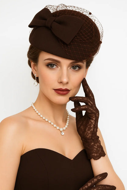 Brown fascinator church hat with birdcage veil and bow for weddings, styled by model
