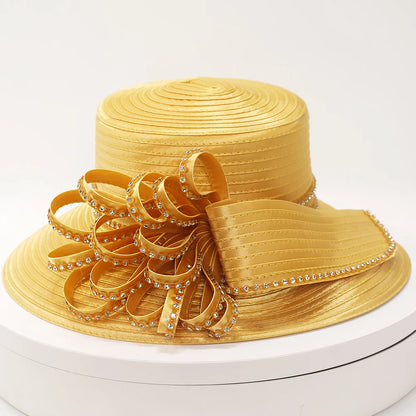 Elegant gold church hat with bow and sparkling rhinestone trim on white background