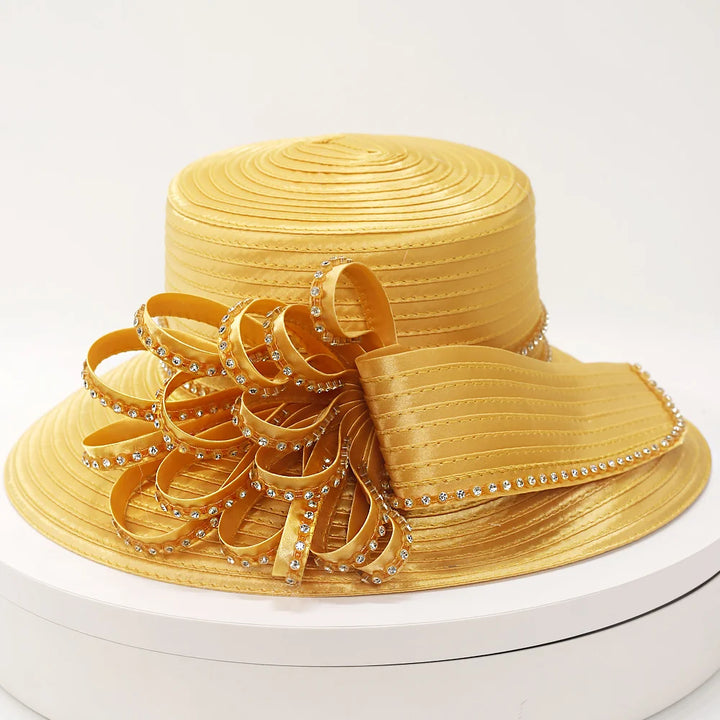 Elegant gold church hat with bow and sparkling rhinestone trim on white background