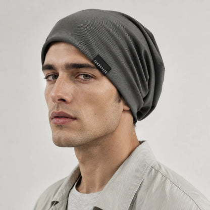Man wearing a dark gray lightweight slouchy beanie with soft ribbed fabric and relaxed back folds