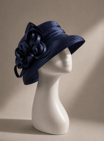 Navy blue cloche church hat with satin flower embellishment and structured short brim for sophisticated Sunday styling.