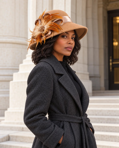 Woman wearing the camel feather-trimmed wool hat with a dark coat outside a stone building