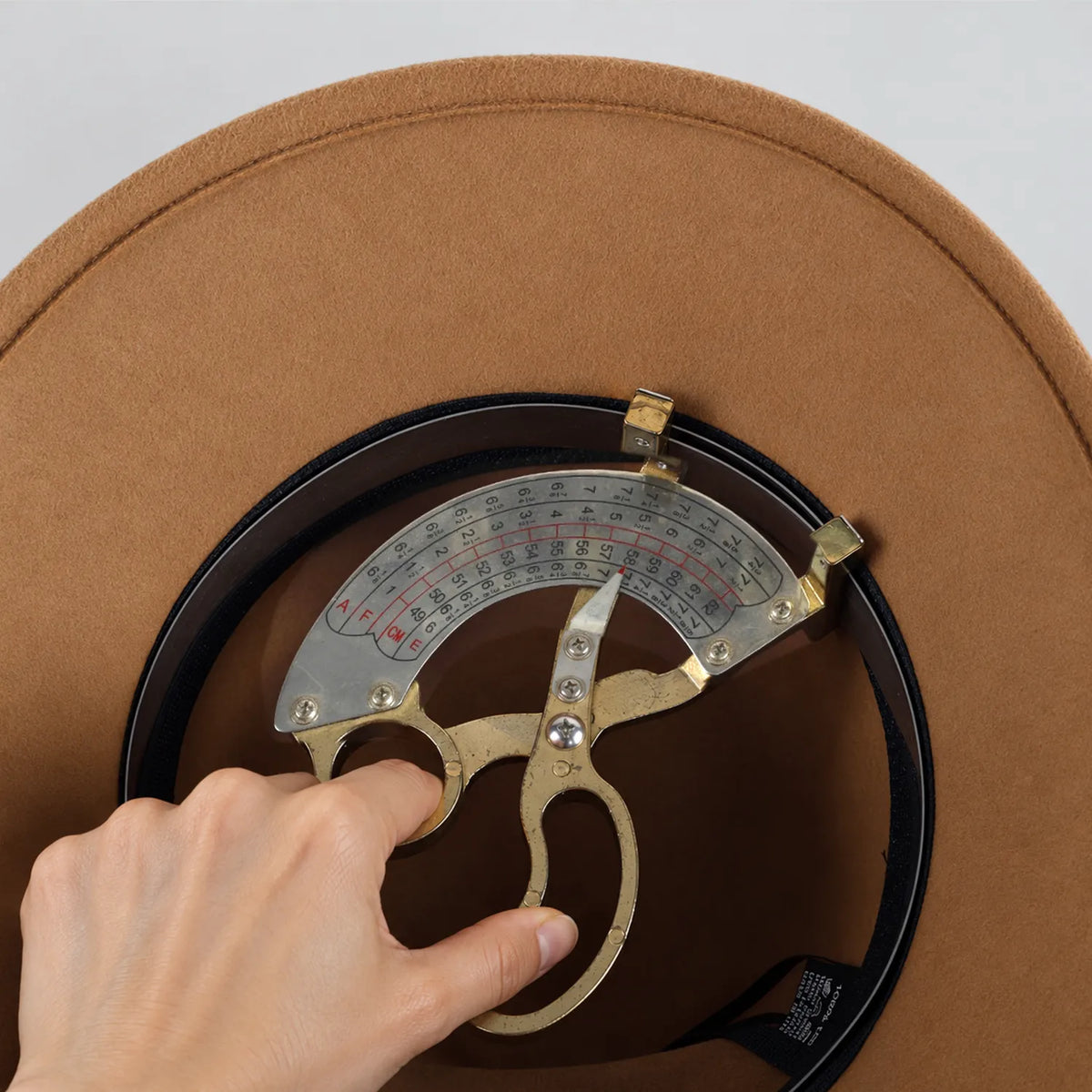 Measuring tool positioned inside the camel Z025M hat beside the inner sweatband