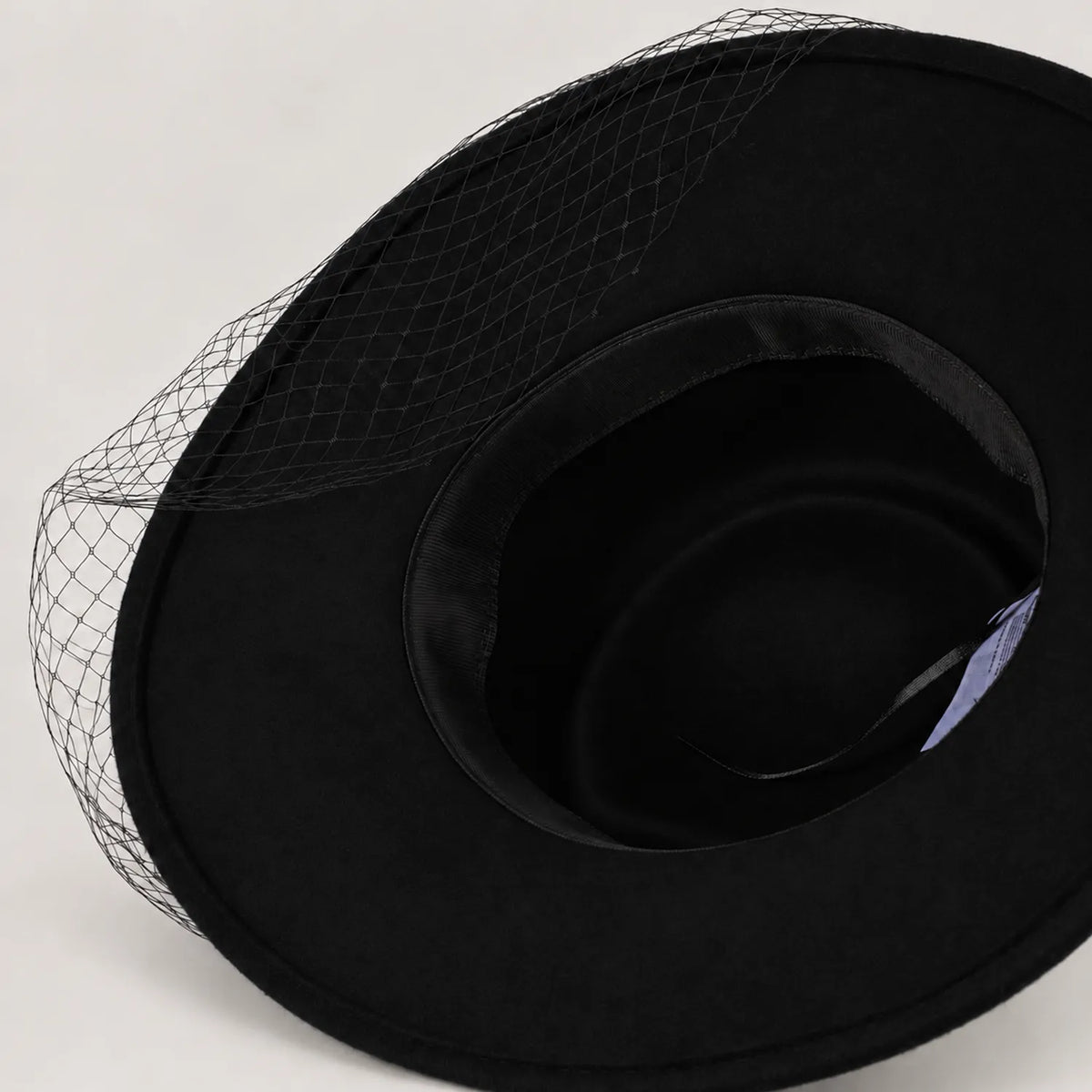 Underside of black Z029B hat showing the unlined interior, inner sweatband, and mesh veil at the brim.