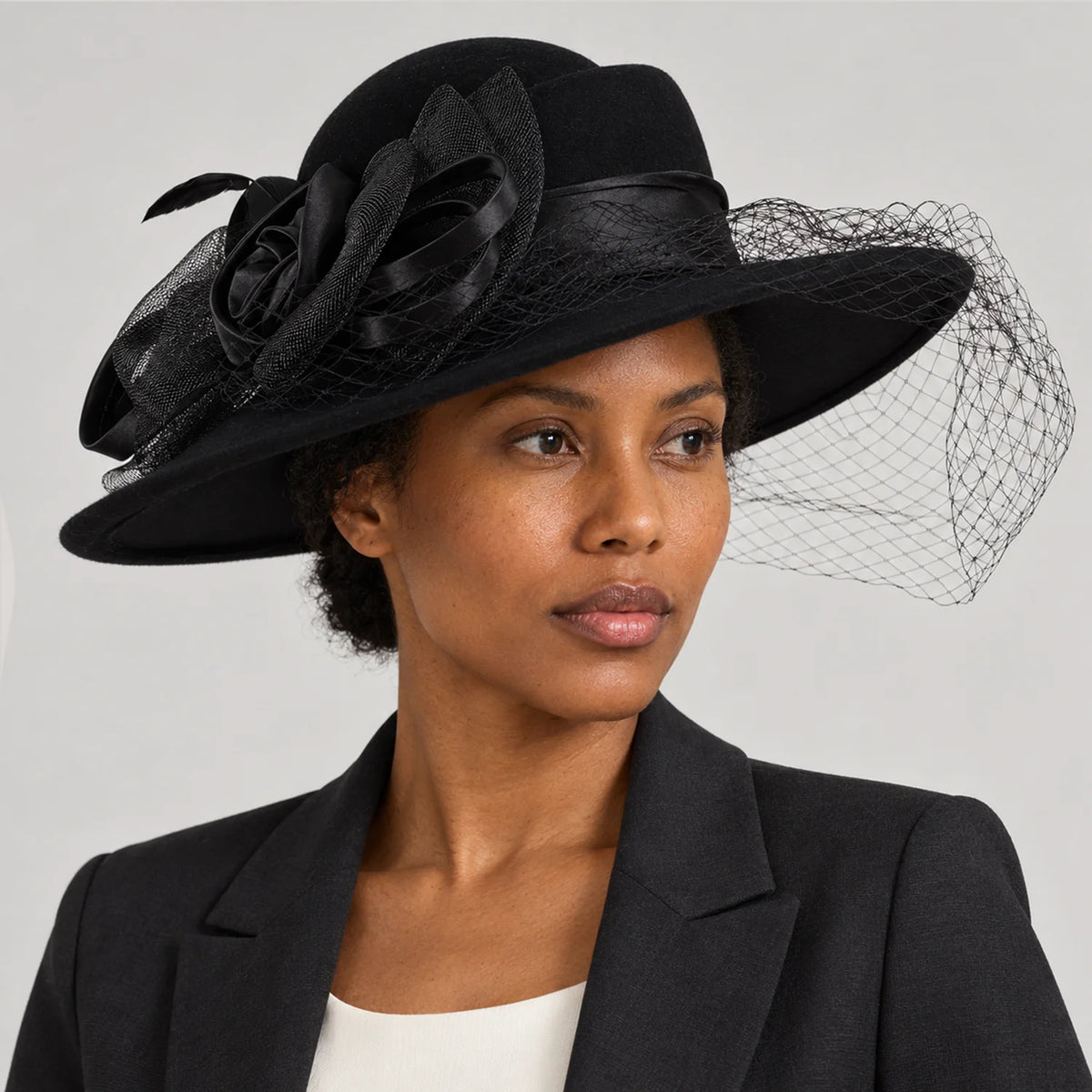 Woman in a dark jacket wearing the black Z029B wide brim hat in a gray studio portrait.