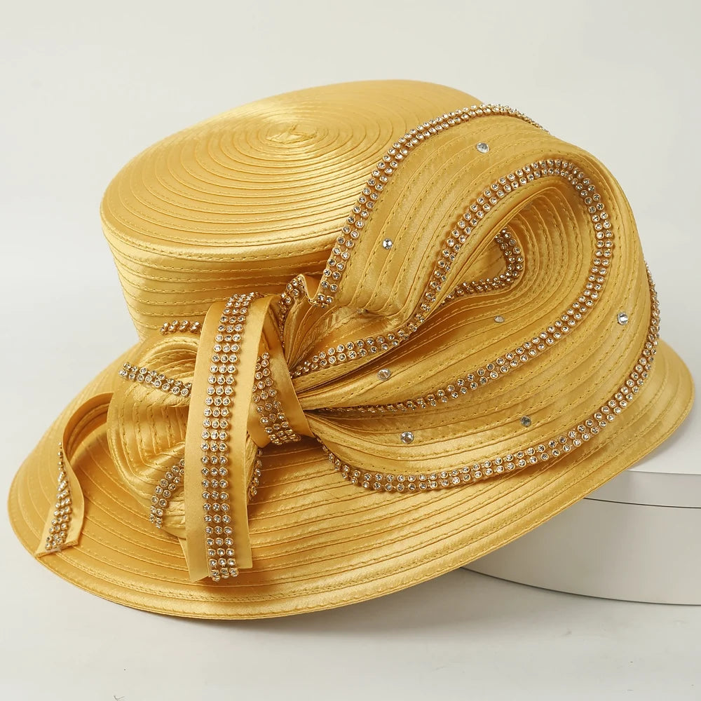 Beautiful gold church hat featuring a large satin ribbon and diamond-like embellishments for a sophisticated and glamorous look.