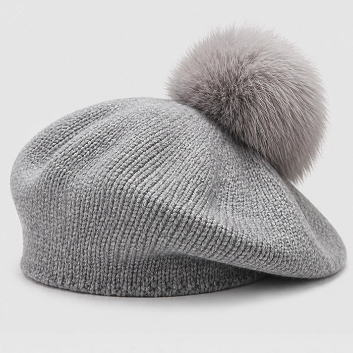 Gray knitted beret with pom-pom, offering elegance and warmth during the winter months.