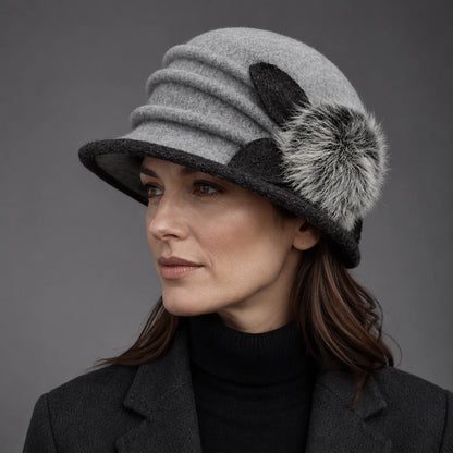 Woman wearing a gray boiled wool cloche hat with a ruched crown and fuzzy pom
