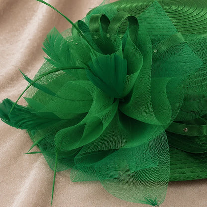 Close-up detail of green church hat featuring mesh floral decoration, feather accents and satin ribbon loops, luxury women’s formal hat