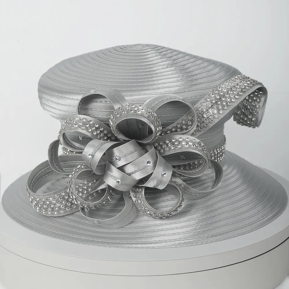 Elegant silver church hat worn by mature woman, adorned with rhinestone loops and satin ribbon, perfect for Sunday service.