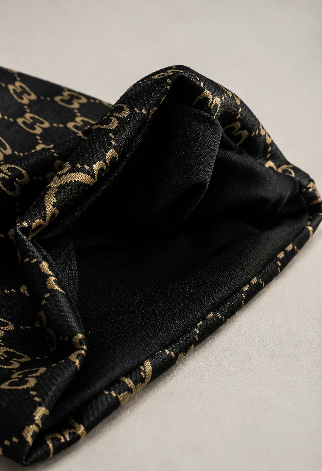 Close-up of black jacquard knit beanie fabric showing premium texture, double C pattern, soft stretch material and detailed craftsmanship.