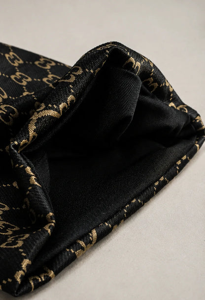 Close-up of black jacquard knit beanie fabric showing premium texture, double C pattern, soft stretch material and detailed craftsmanship.
