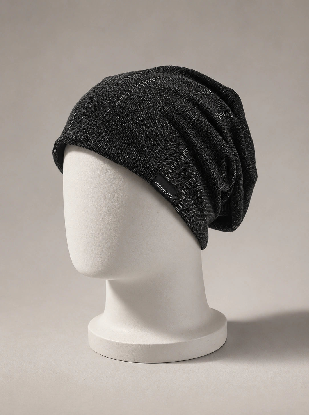 Luxury black slouchy knit beanie displayed on white mannequin with premium minimalist ecommerce photography style