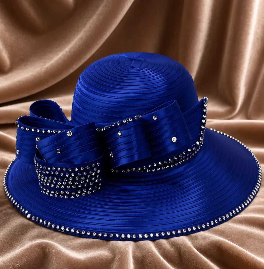 Luxury royal blue church hat with rhinestone trim and decorative bow displayed on satin fabric background for church and special events.