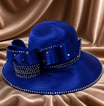 Luxury royal blue church hat with rhinestone trim and decorative bow displayed on satin fabric background for church and special events.