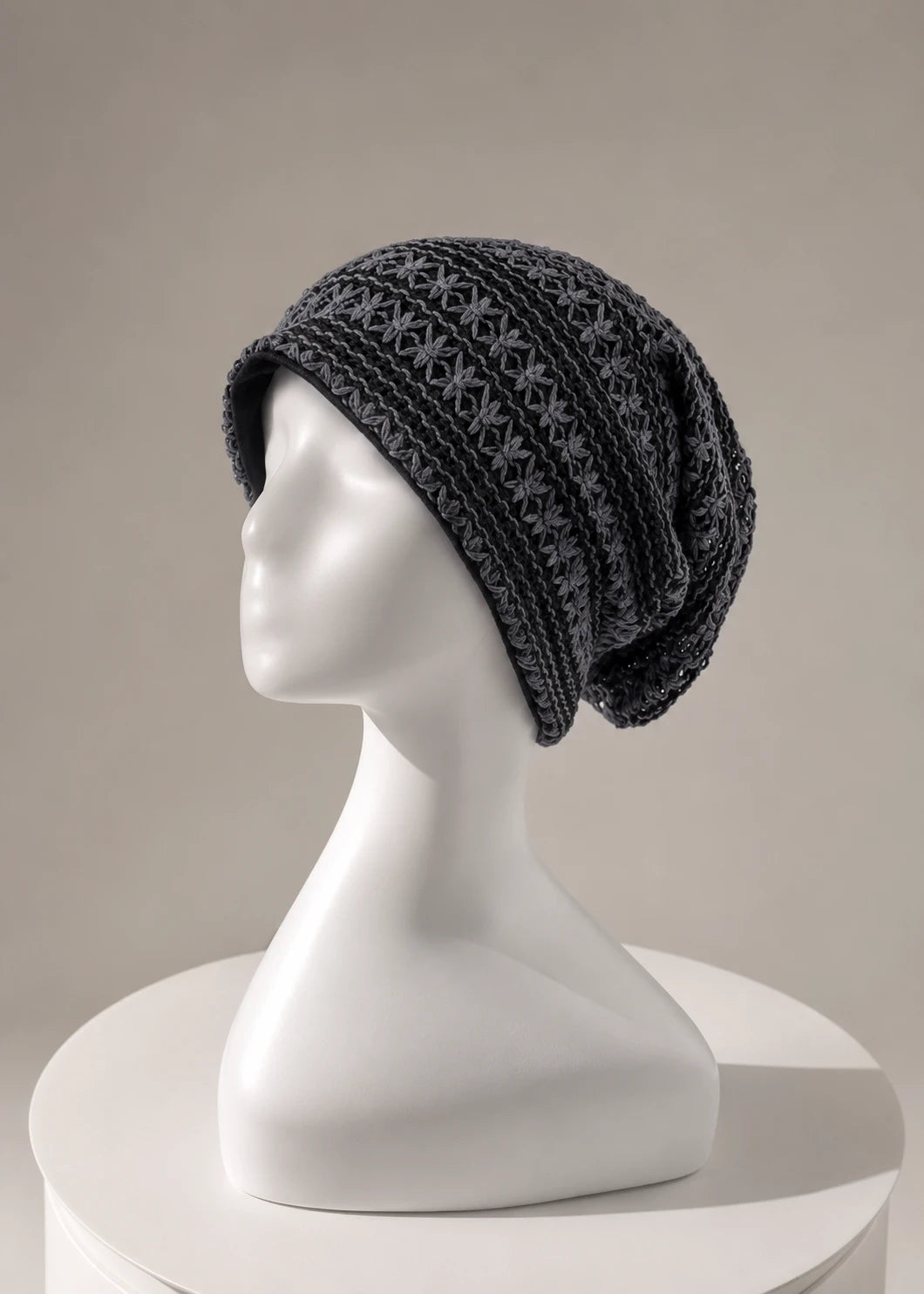 Dark grey crochet slouchy beanie displayed on minimalist mannequin with luxury boutique aesthetic