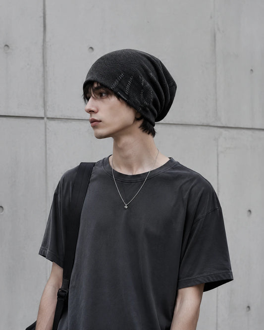 Young man wearing a charcoal black slouchy beanie in minimalist urban streetwear style with relaxed oversized fit