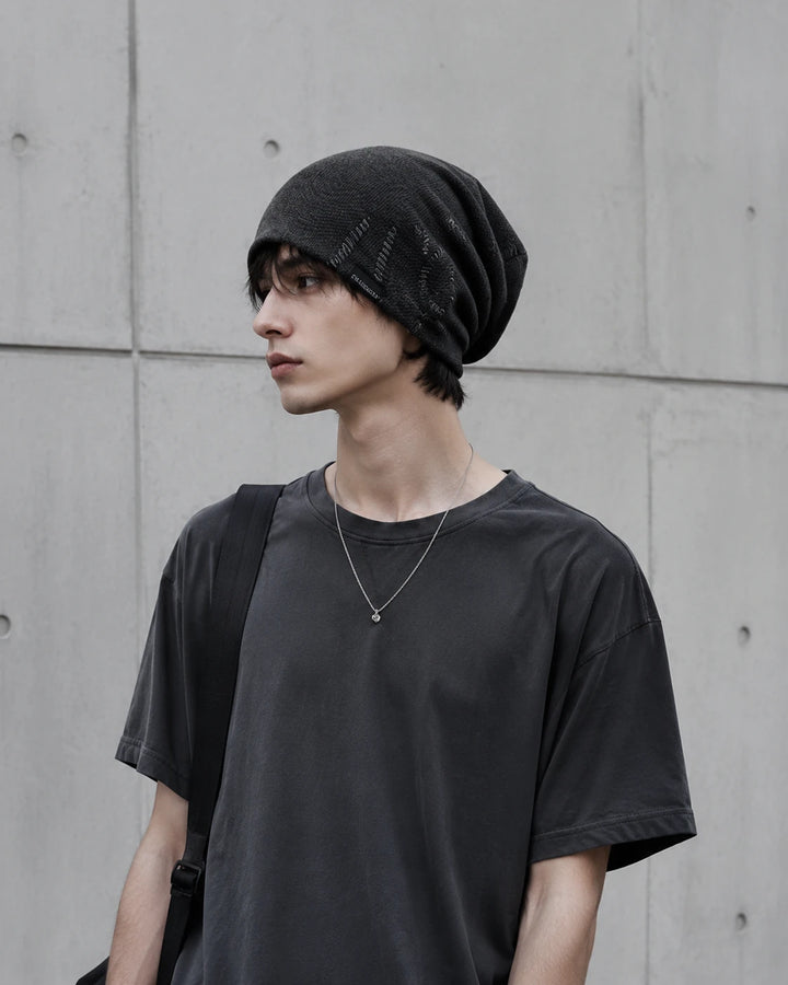 Young man wearing a charcoal black slouchy beanie in minimalist urban streetwear style with relaxed oversized fit