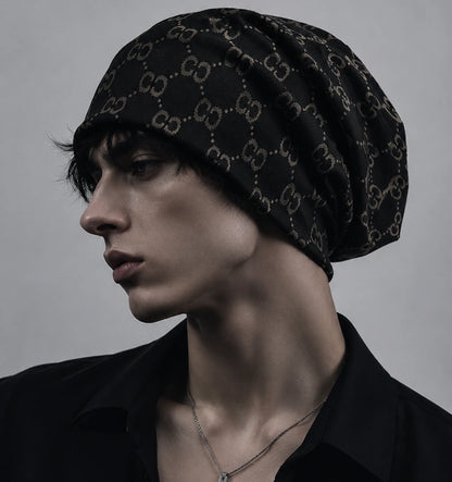 Male model wearing a black oversized slouchy beanie cap with vintage jacquard double C pattern, soft knit fabric, modern streetwear style.