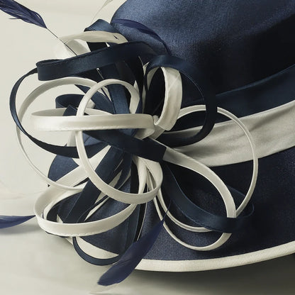 Close-up detail of navy blue and white church hat featuring satin ribbon loops and feather embellishments, luxury formal women’s hat