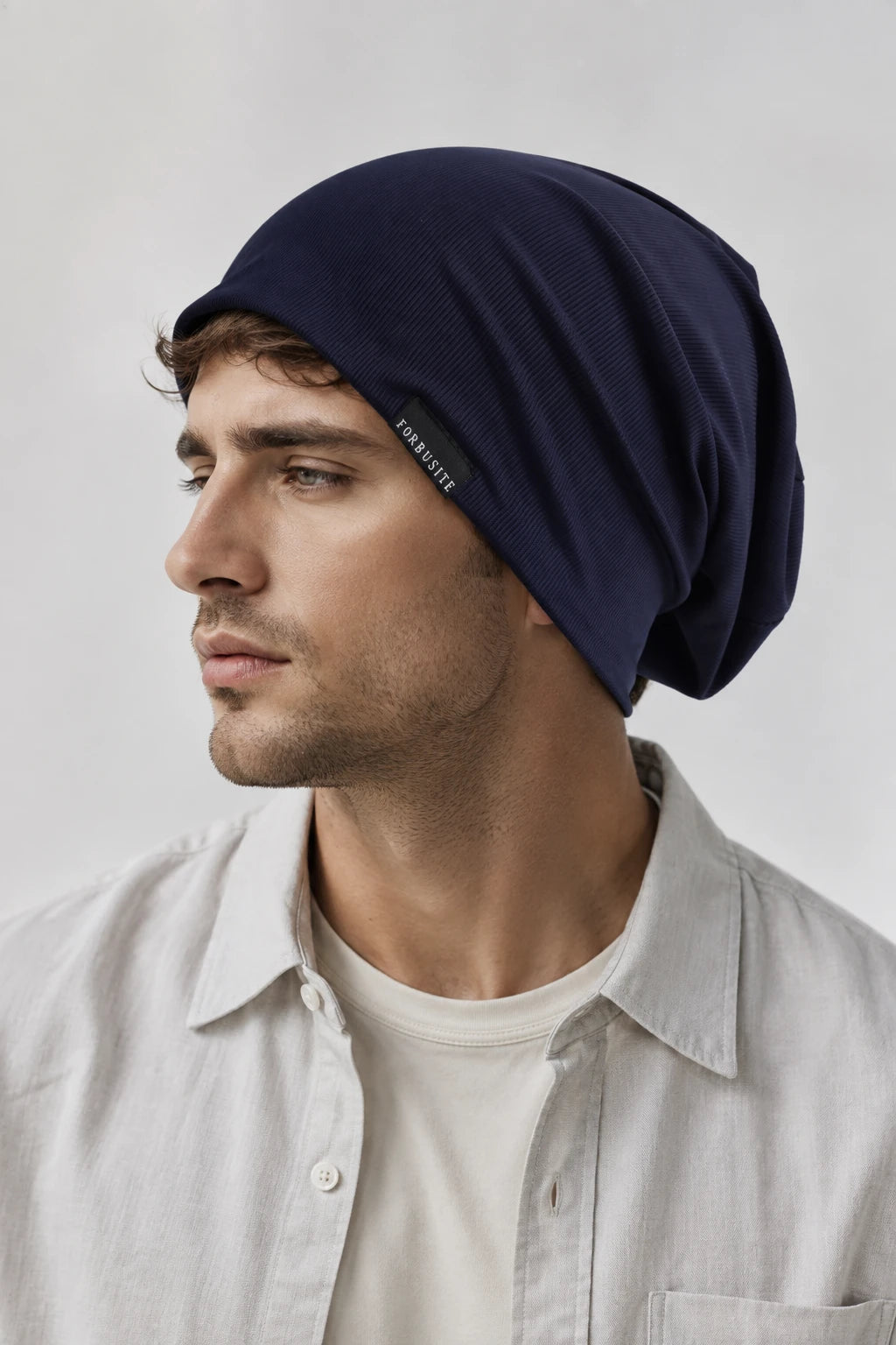 Man wearing a navy blue lightweight slouchy beanie with fine ribbed texture and relaxed fit