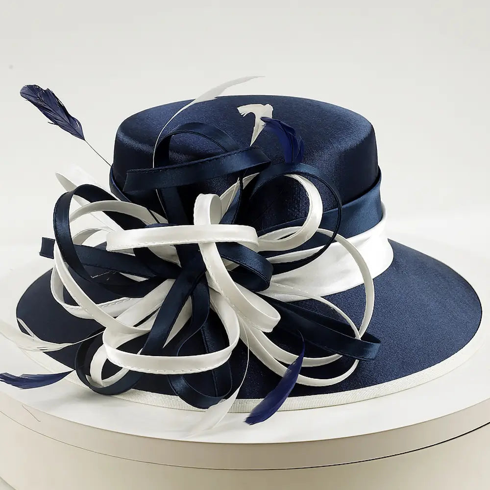 Elegant navy and white satin church hat with large looped ribbon and feather decoration, perfect for formal occasions and weddings.