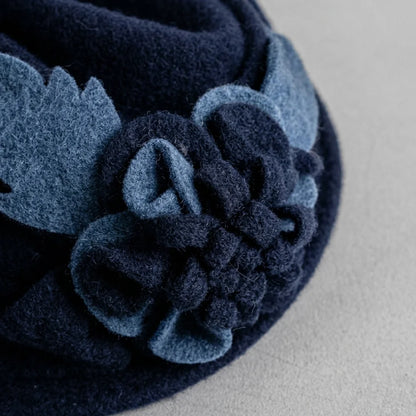 Close-up of the fixed flowers and leaves on a navy wool cloche hat